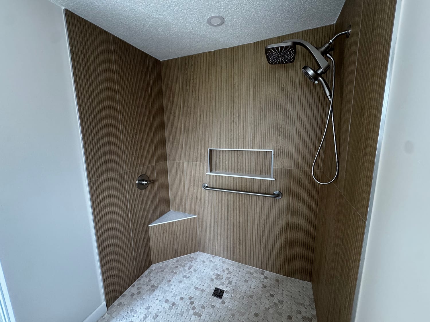 Walk-in tiled shower with wood-look tile and mosaic floor